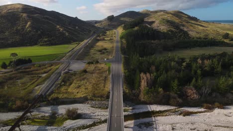 aerial tilt up from road bridge is opening beautiful landscape scenery and wind farm on new zealand coast