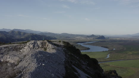 fly over the mountain with an abandoned quarry top of summit, with opening view on the valley with riverbed and mountain ridge in the distance