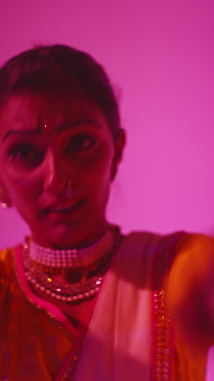 Vertical Video Close Up On Face Of Female Kathak Dancer Performing Dance Wearing Traditional Indian Dress Against Purple Background 1