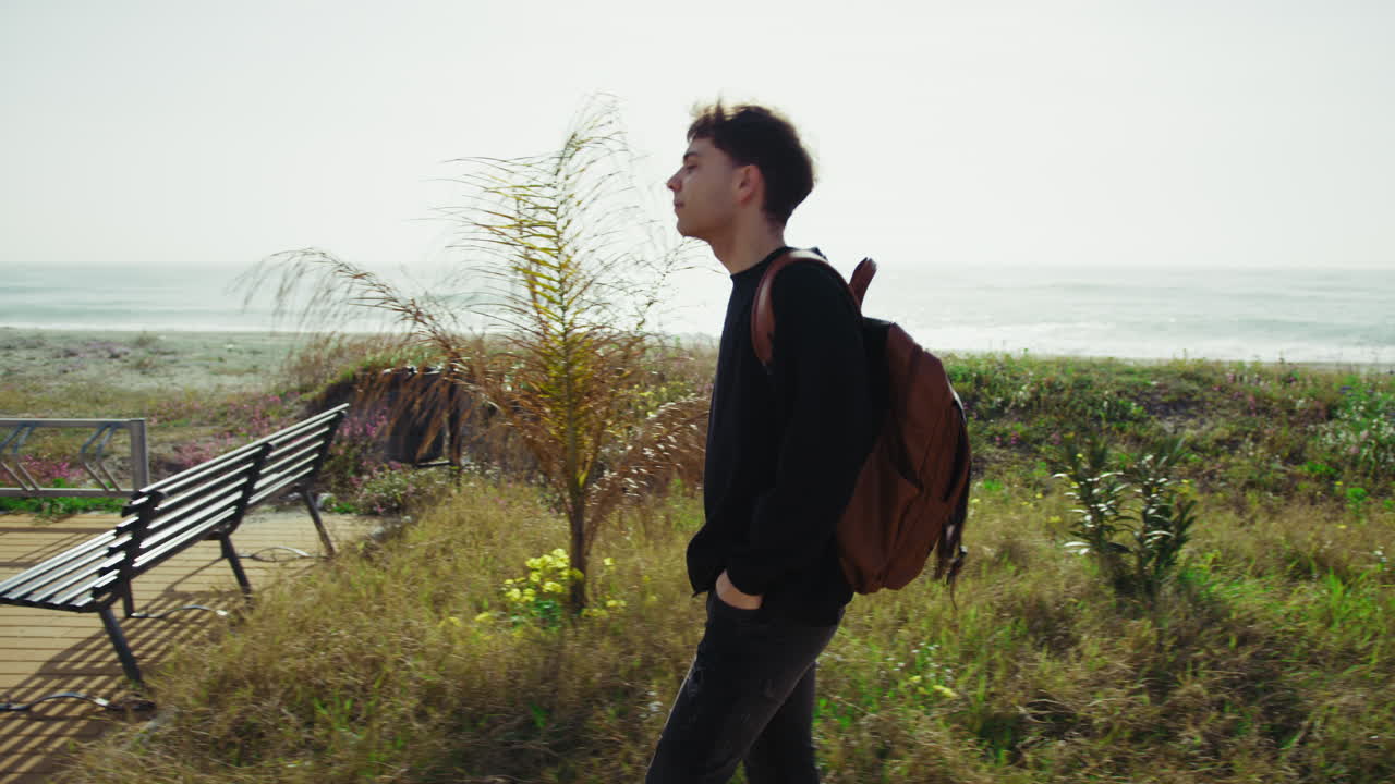 Man Walking Near The Sea With A Backpack After Work