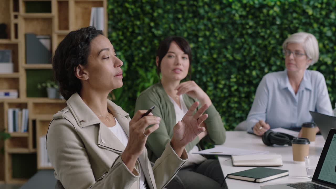 전문 사업가들이 모여 브레인스토밍을 하고 여성 리더가 금융 프로젝트에 대한 창의적인 아이디어를 공유하고 다민족 팀이 사무실 회의실에서 함께 일하고 프레젠테이션을 하고 팀워크를 즐기고 있습니다.