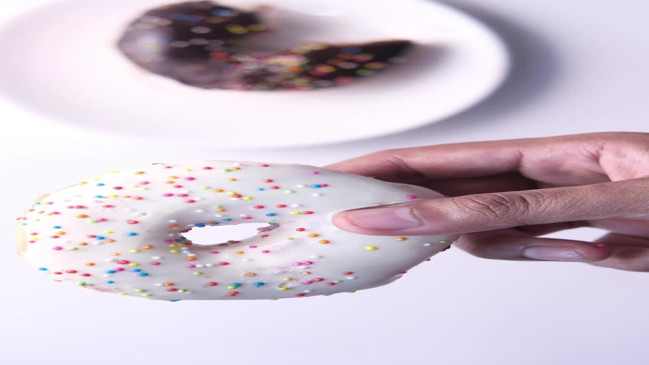 rosquilla blanca de mano con rosquilla de chocolate en el fondo