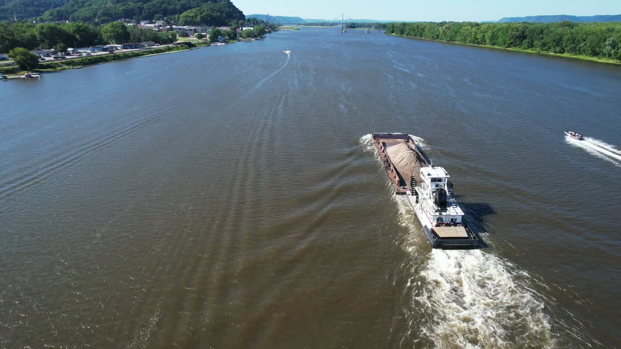 예인선이 미시시피 강에서 아이오와-1 랜싱을 지나 북쪽으로 진흙 바지선 한 척을 밀고 있습니다.