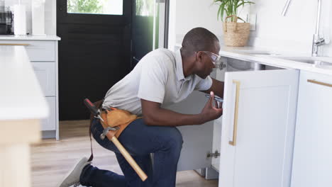 african american plumber is fixing a kitchen sink