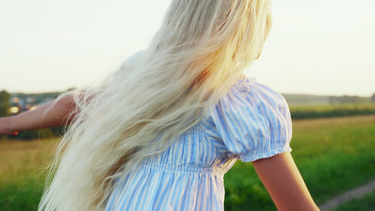Kleines Mädchen mit langen blonden Haaren rennt auf einem sonnigen Feld.