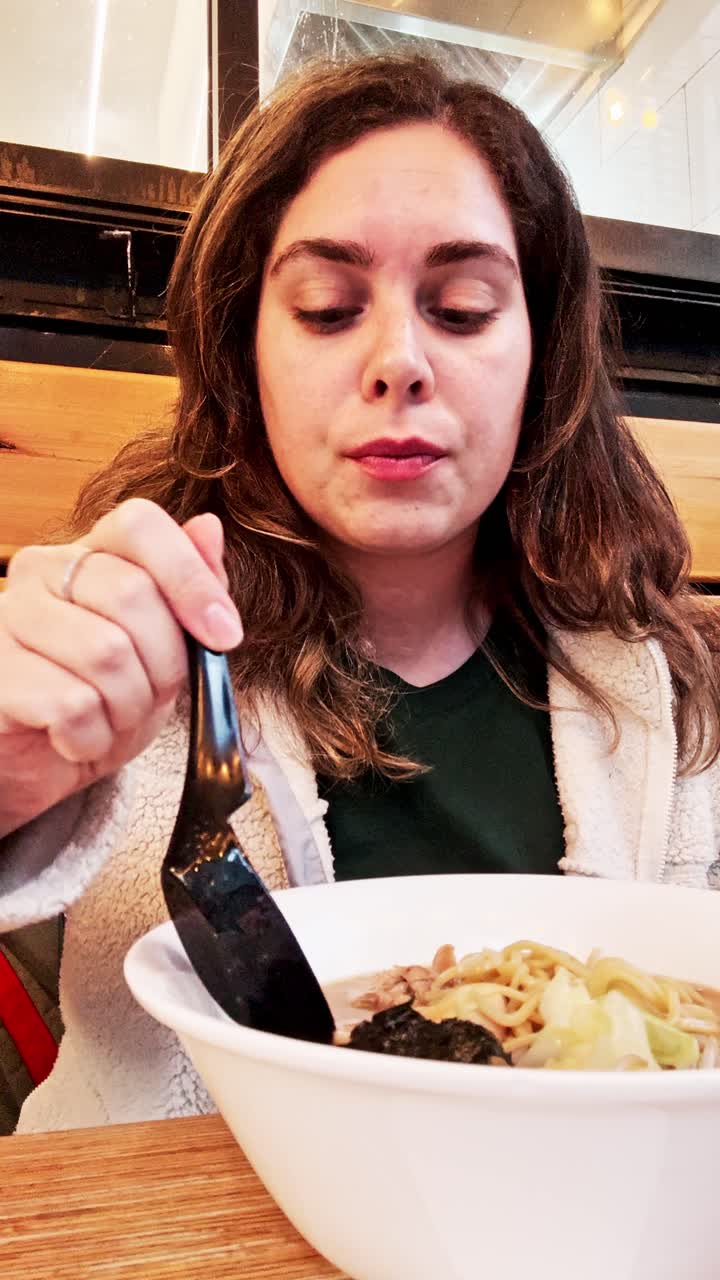 Joven disfrutando de un tazón caliente de sopa ramen.