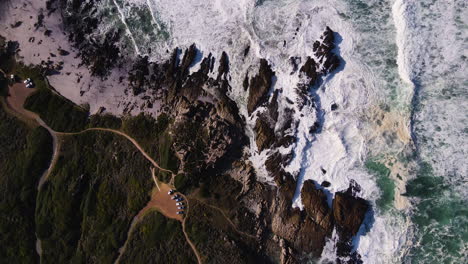 Blick-Von-Oben-Nach-Unten-Auf-Turbulente-Wellen,-Die-Gegen-Die-Felsige-Küste-Schlagen