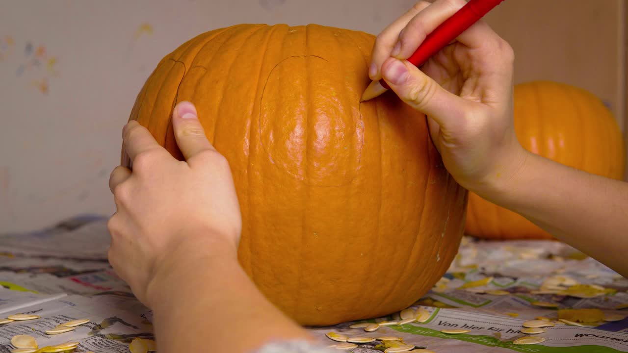 calabaza carvin hembra dibujando cara linda de jack o'lantern en calabaza con bolígrafo preparándose para tallar decoración de halloween