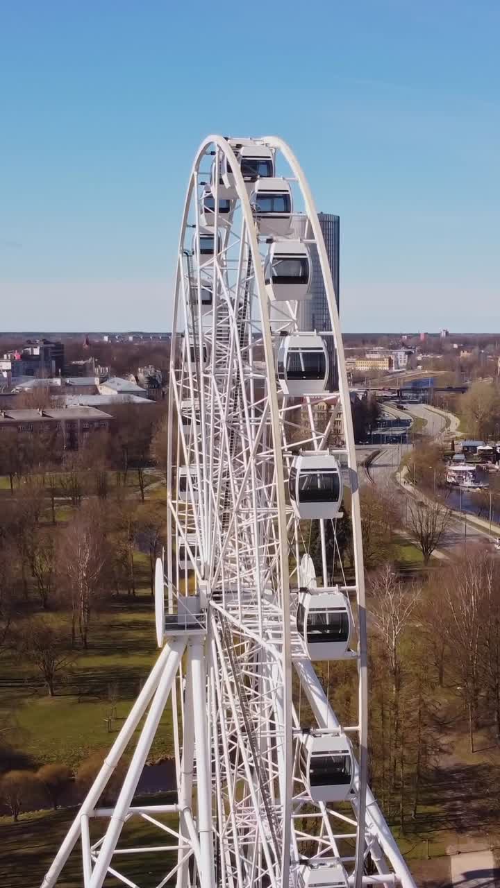 Vertical view of Ferris wheel in Riga with cityscape and business towers in background