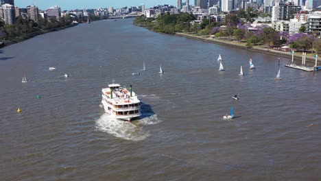 drone shot flying backwards revealing many small boats having a sailing race on the brisbane river, near west end and toowong