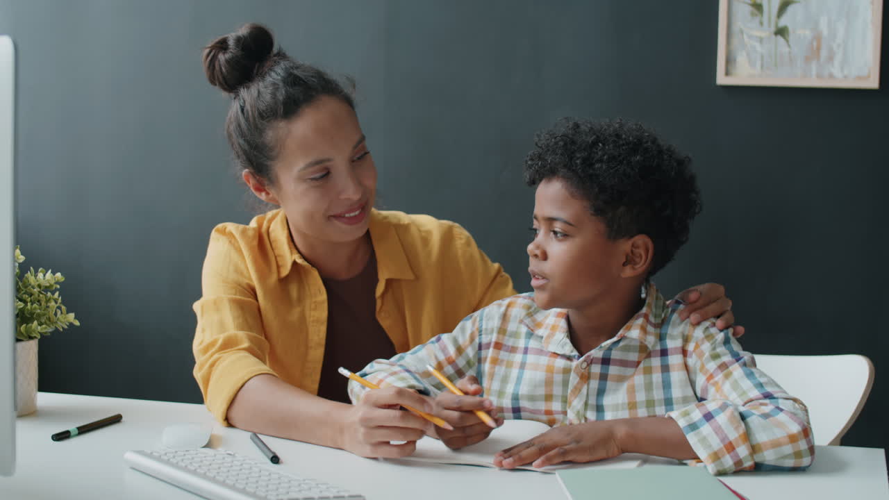 niño africano haciendo la tarea con la ayuda de la madre