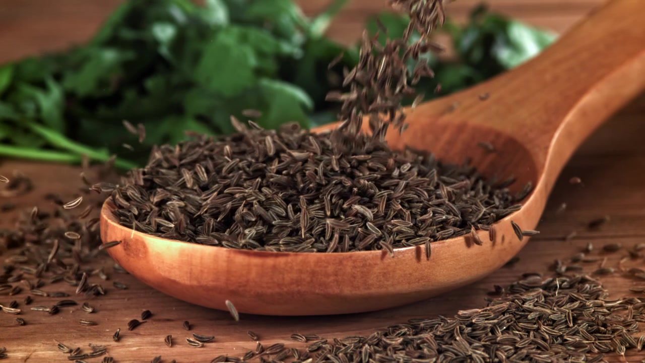 Cumin Seeds Falling into a Wooden Spoon in Slow Motion