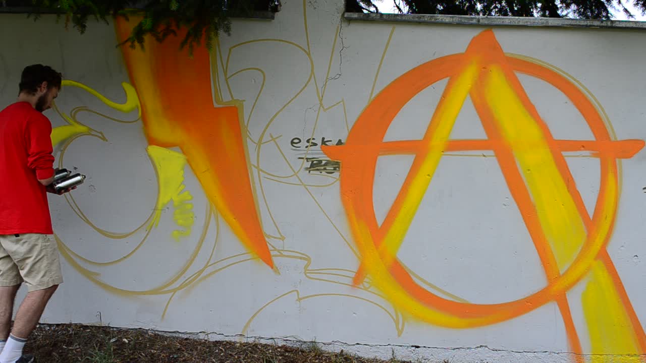Kunstneren tegner graffiti på et gjerde