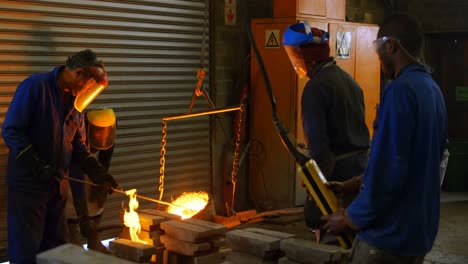 Gruppe-Von-Arbeitern,-Die-In-Der-Werkstatt-Geschmolzenes-Metall-In-Form-Gießen-4k