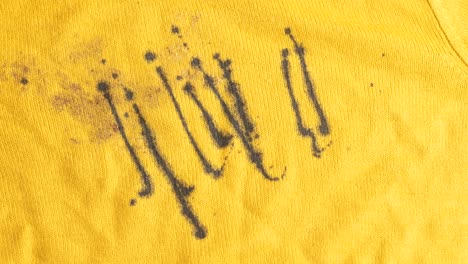 close-up of black stains on vibrant yellow fabric
