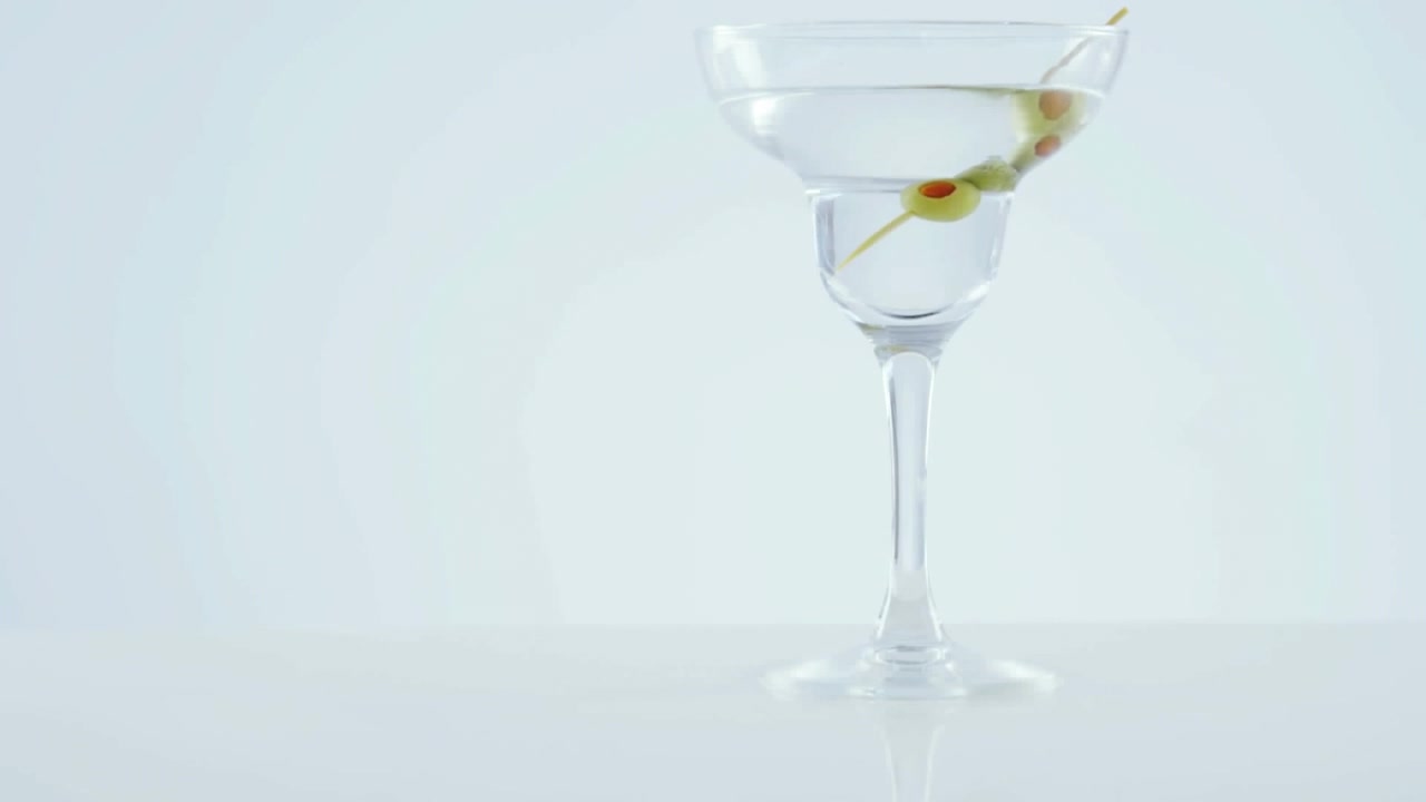 Design a motivo chevron su olive in un bicchiere da cocktail su sfondo grigio.