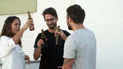 jóvenes felices haciendo sonar botellas de cerveza