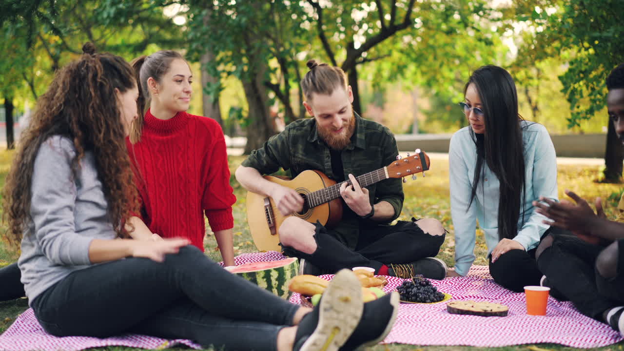 друзья наслаждаются пикником в парке с музыкой