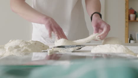 forming and stretching dough balls with hands for homemade pizza in the kitchen at home 4k