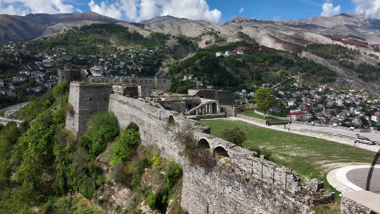 Kamenná pevnost na kopci v Gjirokastëru, Albánie, s horami a městem pod ní.