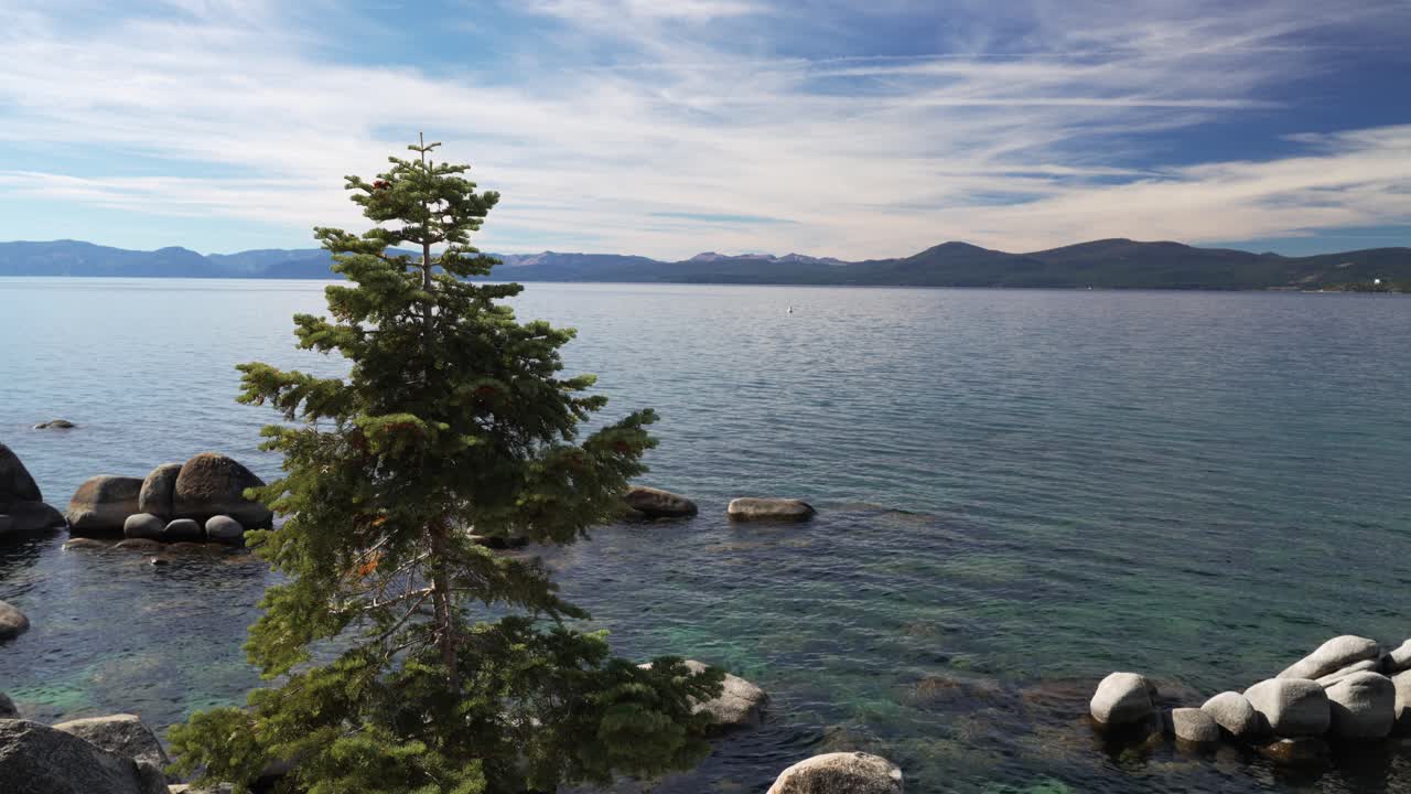 Danau Alpine yang Damai dengan Air Jernih, Garis Pantai Berbatu, dan Pohon Hutan