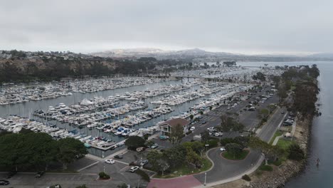 aerial drone view over a sailboat and boats, at a harbor, in gloomy, overcast california