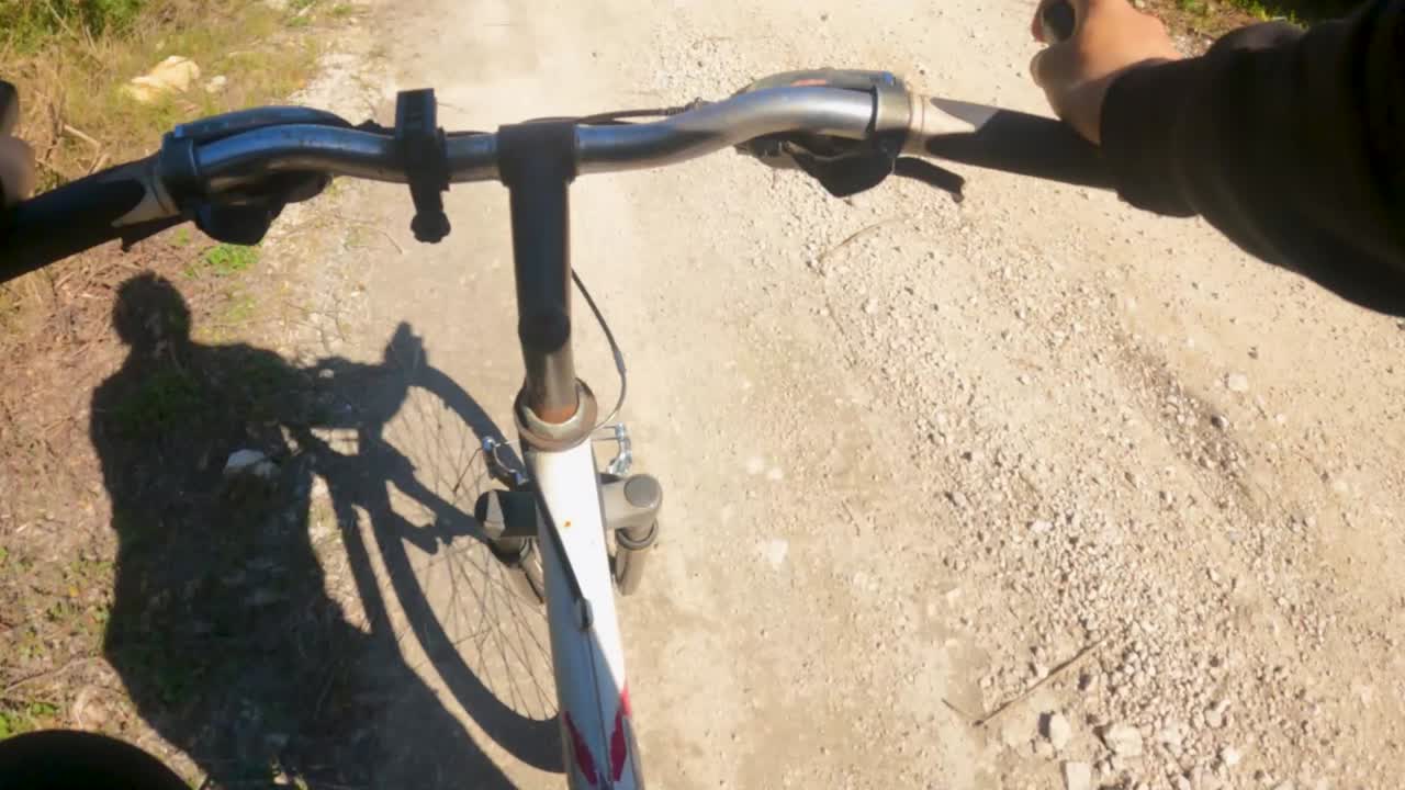 POV Punto di vista: andare in bicicletta su sterrato e sentieri di ghiaia in una zona di campagna immersa nella natura, un'avventura ciclistica e un'attività fisica all'aperto in una giornata di sole a Corfù, in Grecia