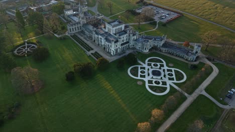 aerial view of ashridge house in evening light with formal lawn patterns and british countryside, hertfordshire, england