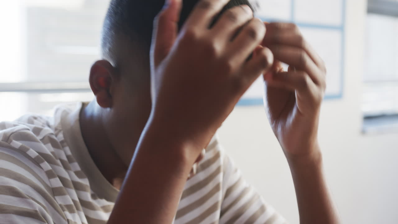 A scuola, ragazzo che si concentra sul suo lavoro in classe, indossando una maglietta a righe.