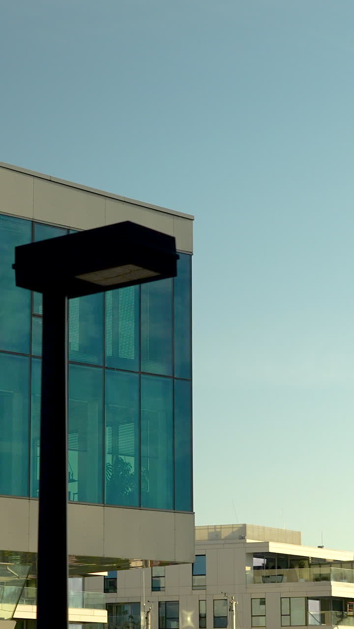 Una elegante toma vertical de edificios de oficinas contemporáneos y arquitectura residencial con fachadas de cristal azul. Perfecto para contenido de bienes raíces y desarrollo urbano.