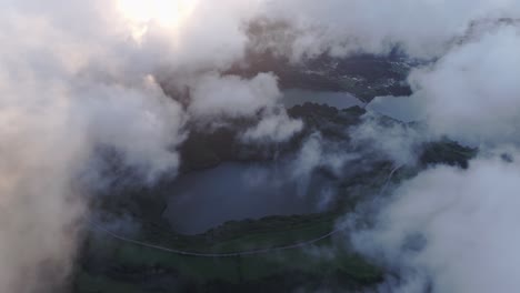 flying over lagoa das sete cidades lake with low clouds at sunset, aerial