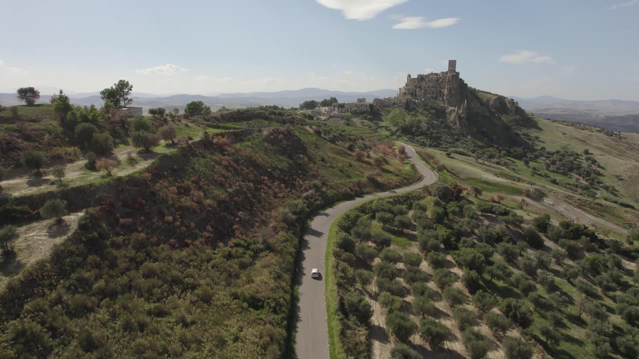 4k에서 이탈리아 남부의 언덕에서 크라코의 오래된 폐허를 향해 운전하는 차를 따르는 드론