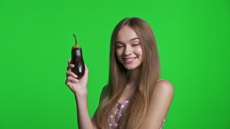 chica sonriente con vestido de verano sonriendo y sosteniendo berenjena