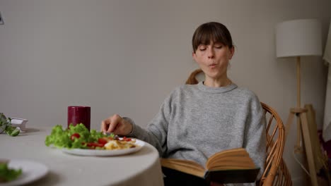 woman eating breakfast and reading a book at home