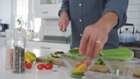 hombre caucásico mayor feliz en la cocina, cortando verduras para una comida y sonriendo