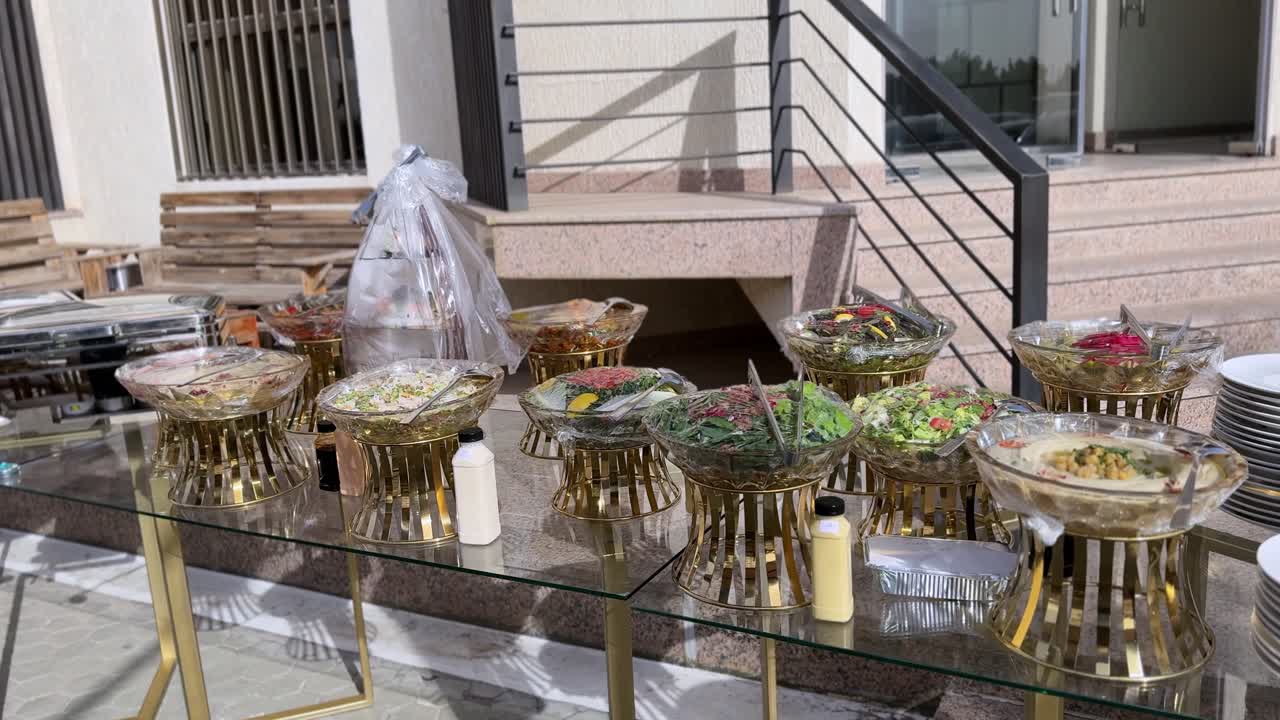 Elegante montaje de catering en Kuwait con hummus fresco y ensaladas en boles de cristal sobre soportes decorativos dorados. Ideal para hostelería, catering de bodas y expositores de eventos profesionales.