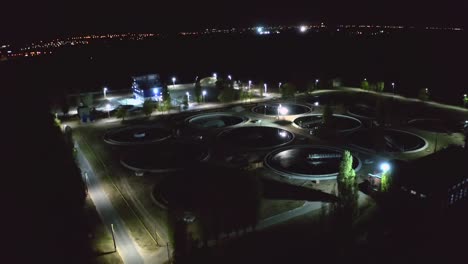 aerial night view of modern wastewater treatment plant with round pools for cleaning sewage