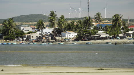 poor coastal homes of vietnamese people and expensive modern wind turbines in background