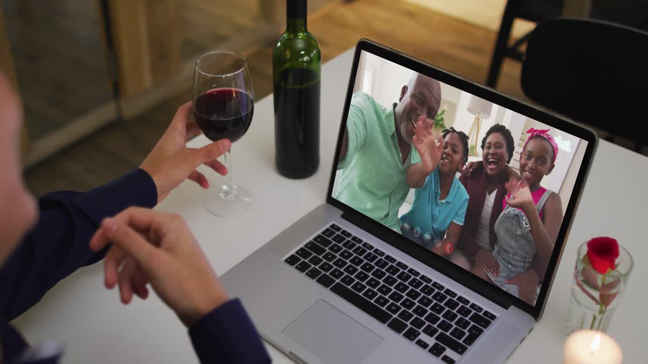 Mulher afro-americana bebendo vinho durante uma videochamada no notebook em casa