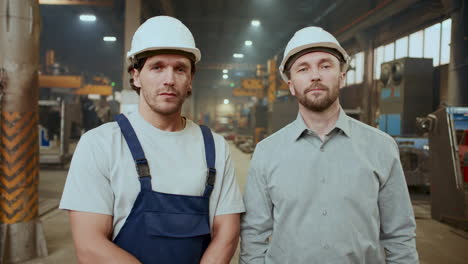 portrait of engineer and technician in hard hats standing in industrial plant