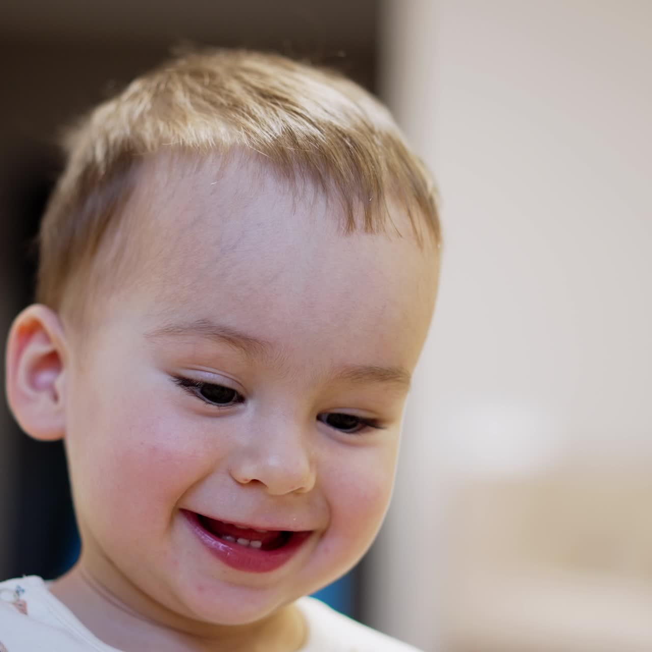 Happy healthy Caucasian toddler smiling adorably to the camera. Kid is joyful for getting a toy. Close up portrait