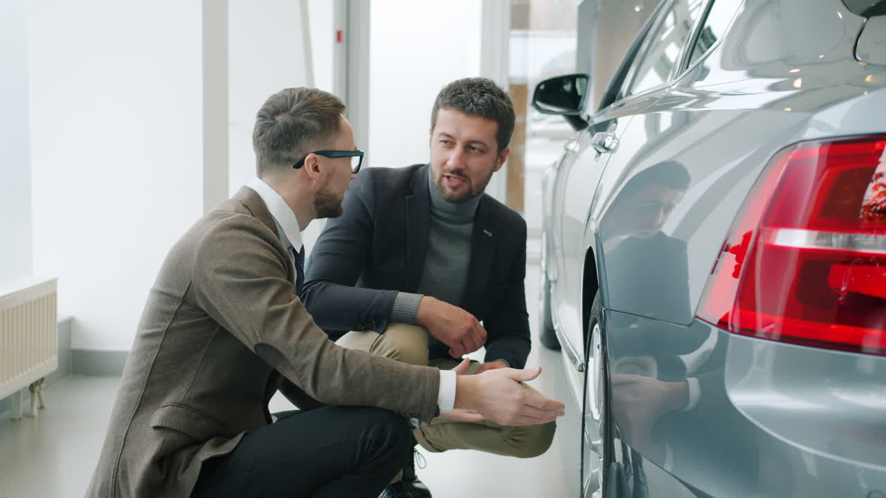 Two Men Inspecting a Car in a Showroom