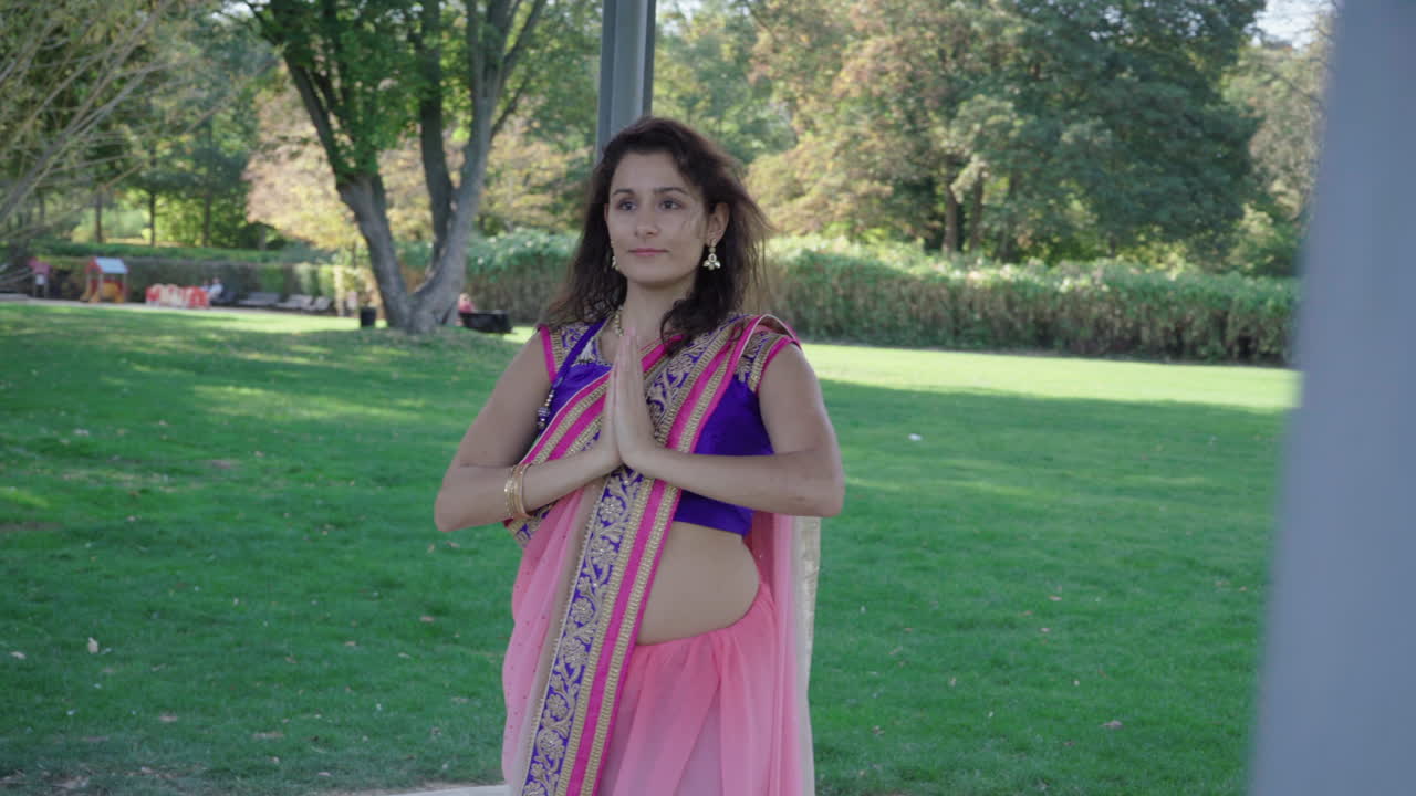 Giovane donna con un sari colorato che balla in un parco