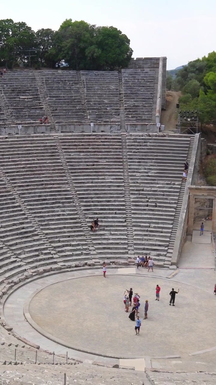 Antico Teatro di Epidauro che si rivela da dietro gli alberi