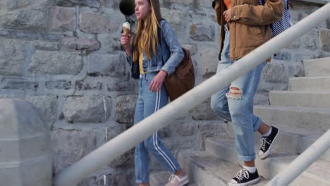 side view of a caucasian and a mixed race girl eating ice cream seaside