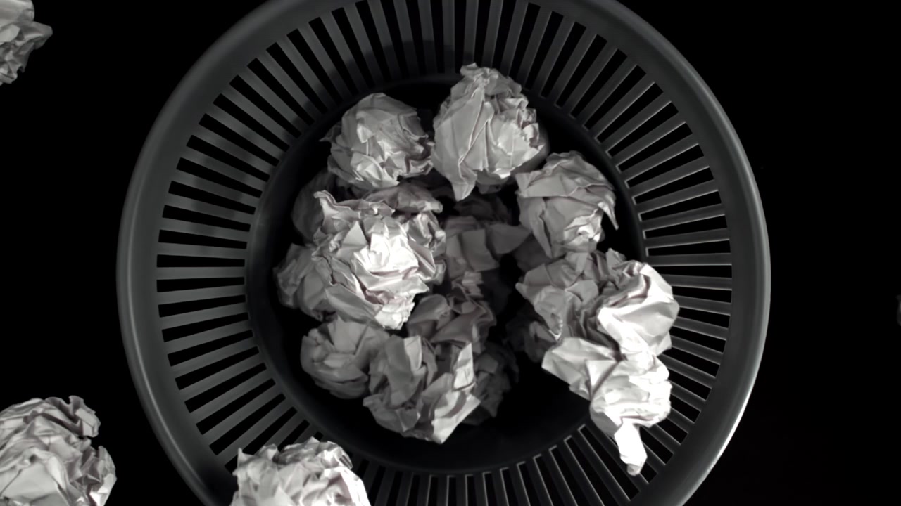Palline di carta accartocciate che cadono in un cestino