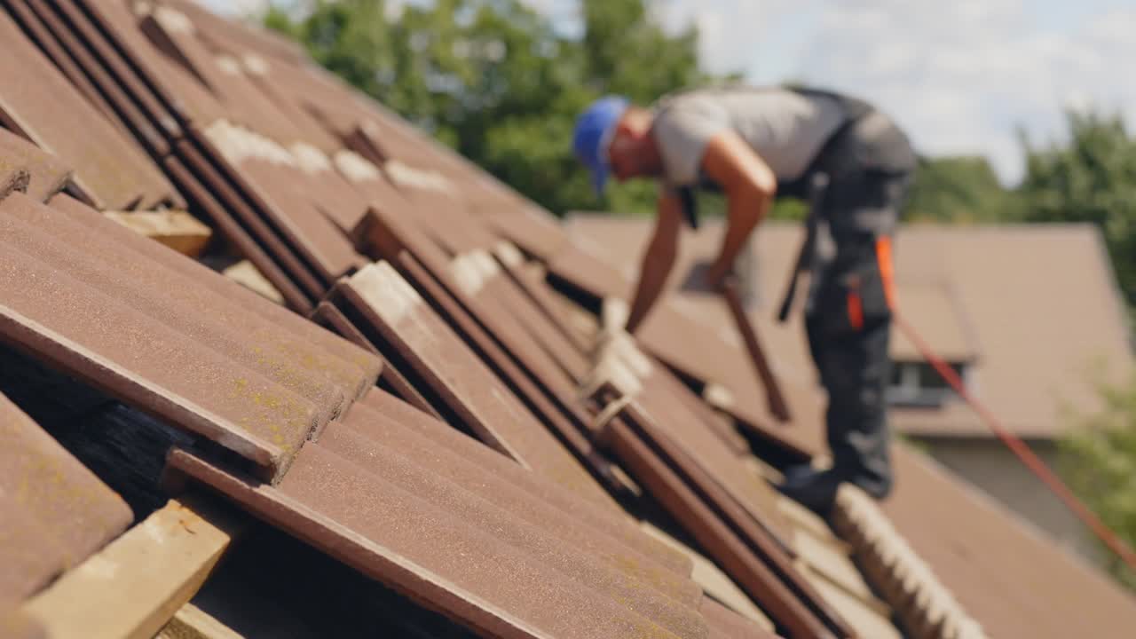 Tegolista professionista sul tetto con imbracatura di sicurezza che posa le tegole.