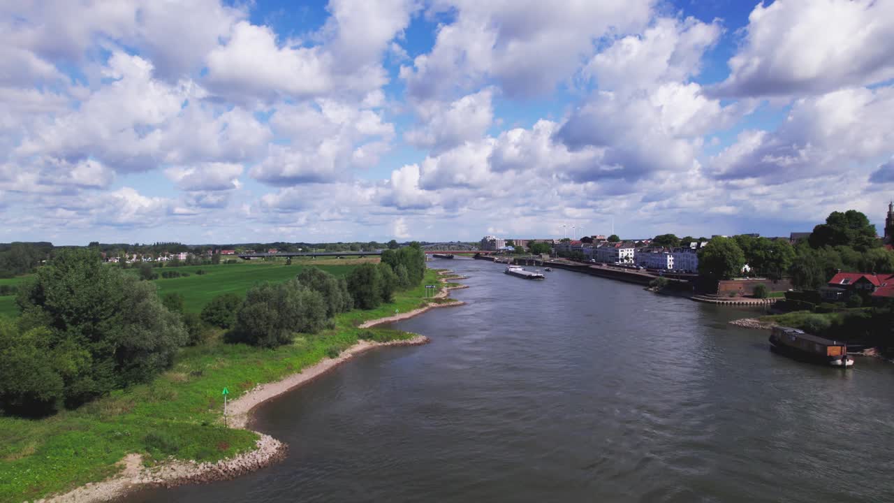 Cargo ships awaiting and passing through steel draw bridge at Zutphen on the overflown river IJssel during high water level. Aerial inland shipping waterway infrastructure concept