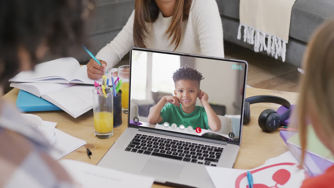 estudiantes diversos usando una computadora portátil para una videollamada con un escolar biracial en la pantalla