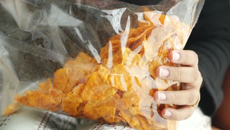 hand opening a bag of spicy chips